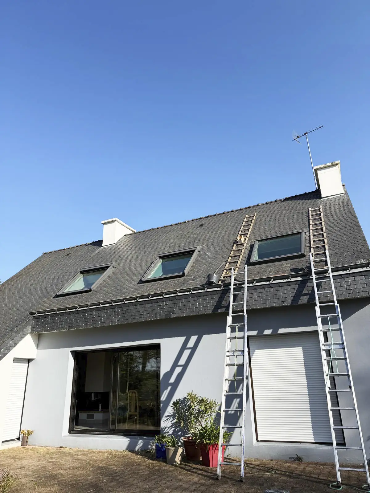Intervention sur une toiture en ardoise avec des échelles de couvreur installées pour un accès sécurisé.
