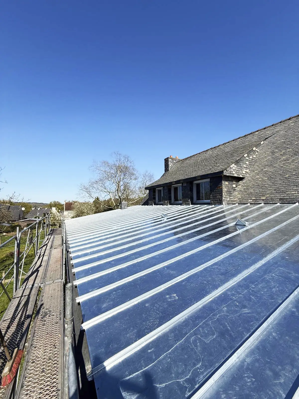 Vue d'ensemble d'une toiture d'extension en zinc à Languidic avec échafaudage sur le côté.