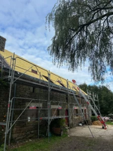 Rénovation en cours d'une toiture en ardoise sur maison en pierre à Bubry