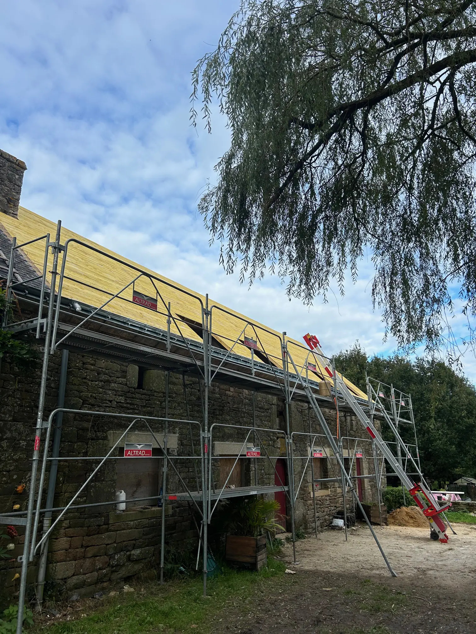 Rénovation en cours d'une toiture en ardoise sur maison en pierre à Bubry