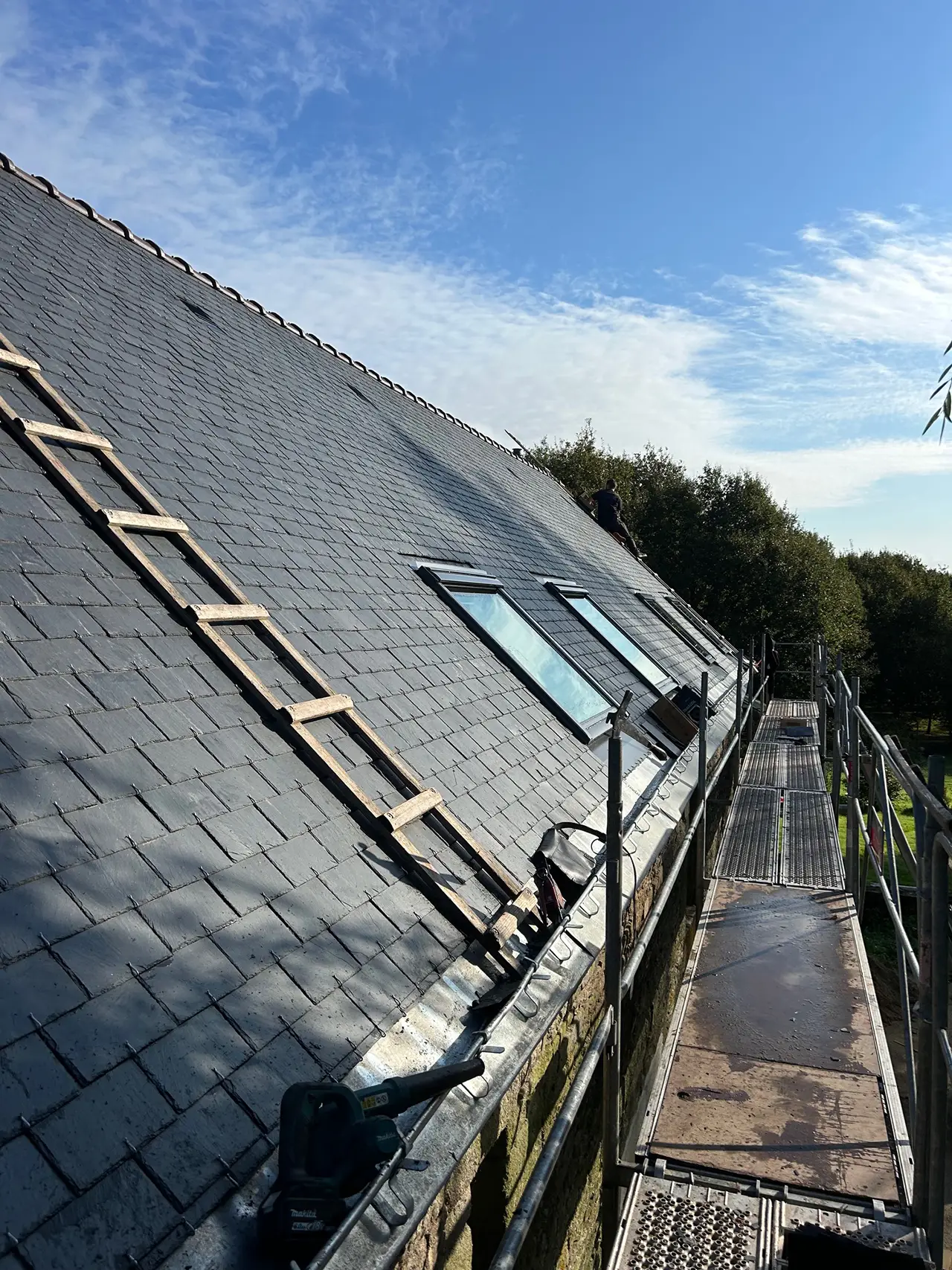Vue du chantier de couverture en ardoise à Quistinic presque terminée, avec intégration de fenêtres de toit Velux.