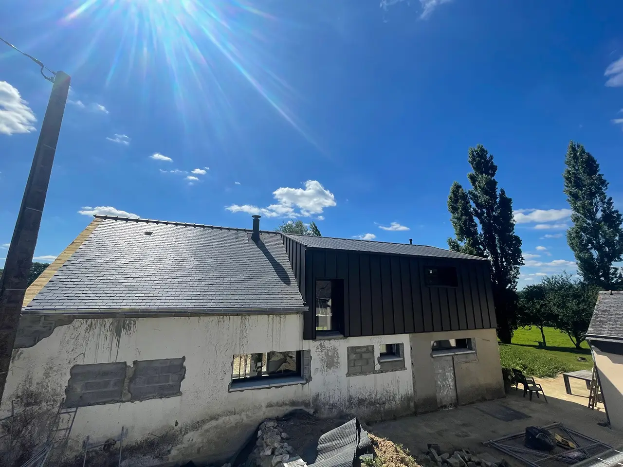 Maison à Inguiniel rénovée par Rolland Toitures, alliant couverture ardoise et bardage en zinc noir à joint debout.