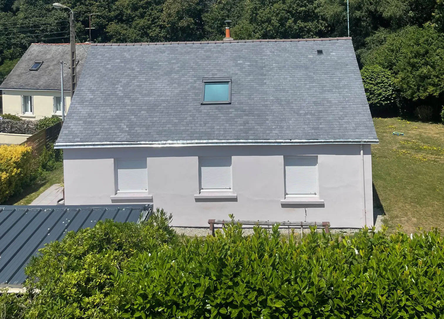 Maison individuelle à Guidel avec une toiture en ardoise entièrement rénovée et une fenêtre de toit Velux.